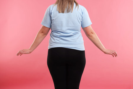 Weight loss. Plus size woman on pink background, closeupの写真素材