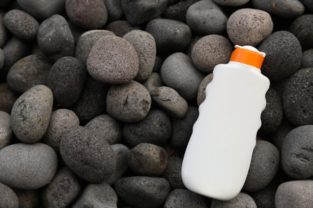 Bottle of sun protection product on pebbles, top view. Space for textの写真素材