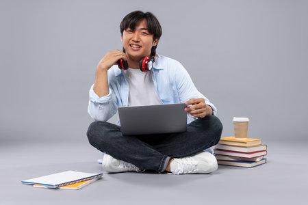 Student with headphones and laptop on gray backgroundの写真素材