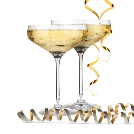 Glasses of sparkling wine and golden serpentine streamers on white backgroundの写真素材