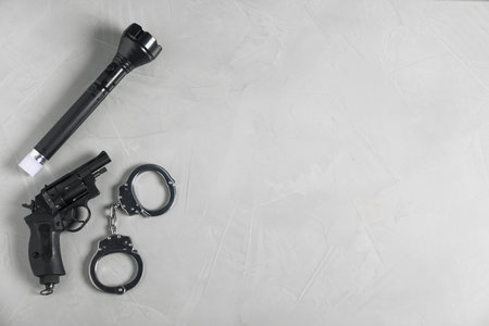 Gun, handcuffs and flashlight on light grey table, flat lay. Space for textの写真素材