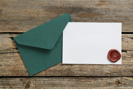 Blank invitation card and envelope on wooden table, top view. Space for designの写真素材