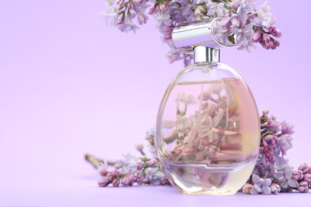 Bottle with perfume and lilac flowers on violet gradient background, closeup. Space for textの写真素材