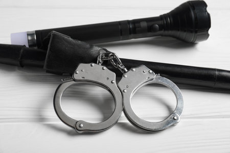 Flashlights and handcuffs on white wooden table, closeup. Police equipmentの写真素材