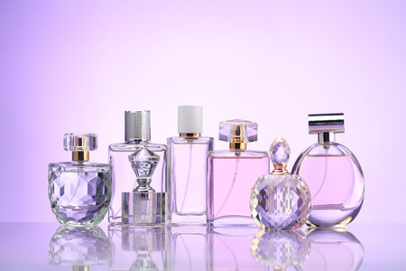 Bottles of perfume on mirror surface against pale violet gradient backgroundの写真素材