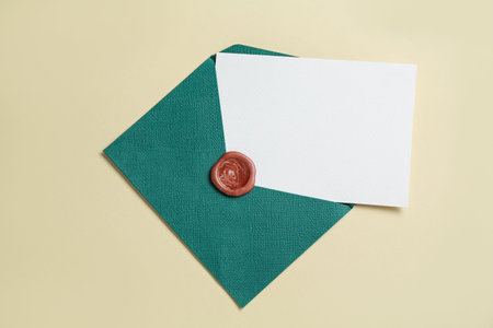 Blank invitation card and envelope on beige background, top view. Space for design