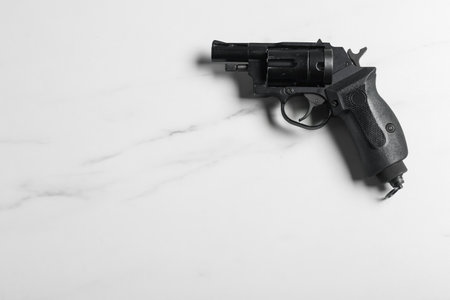 Police equipment. One black gun on white marble table, top view. Space for textの写真素材