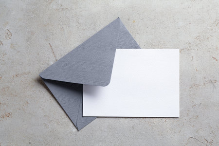 Blank invitation card and envelope on light grey table, top view. Space for designの写真素材