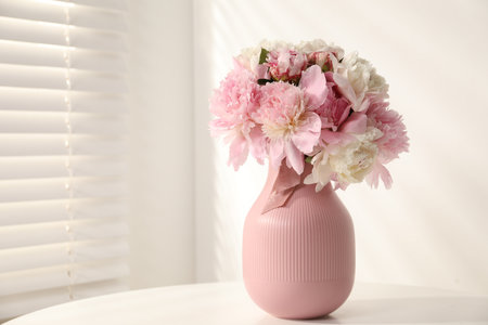 Bouquet of beautiful peonies in vase on white table indoors. Space for textの写真素材