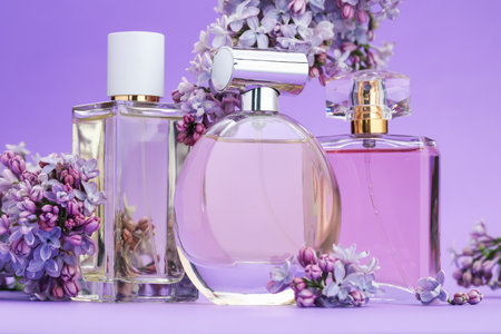 Bottles with perfumes and lilac flowers on purple gradient background, closeupの写真素材