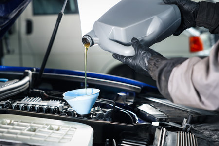 Worker pouring motor oil from canister into car engine, closeupの写真素材