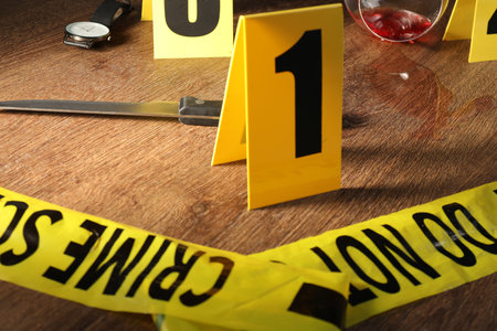 Forensic expert. Yellow crime scene tape, markers and evidences on wooden table, closeupの写真素材