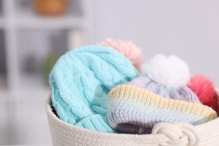 Different wool hats in basket indoors, closeup