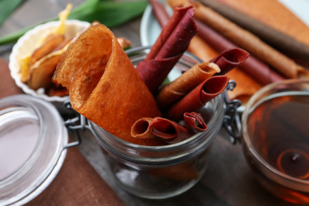 Tasty fruit leather rolls and tea on wooden table, closeupの写真素材