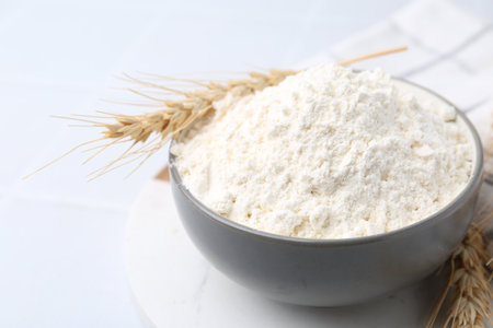 Wheat flour and spikes on white tiled table, closeupの写真素材