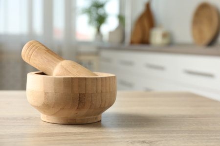 Mortar and pestle on wooden table in kitchen, closeup. Space for textの写真素材