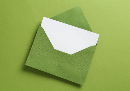 Blank invitation card and envelope on green background, top viewの写真素材