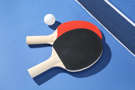 Ping pong rackets, ball and net on blue background, closeupの写真素材