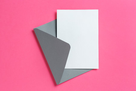 Blank invitation card and envelope on pink background, top view. Space for designの写真素材