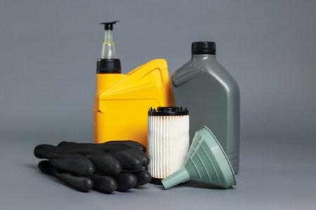 Motor oil in plastic canisters, filter, gloves and funnel on gray backgroundの写真素材