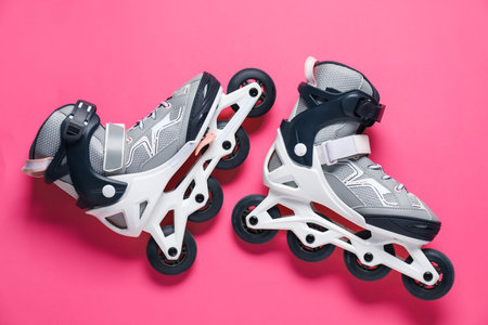 Pair of roller skates on pink background, top view