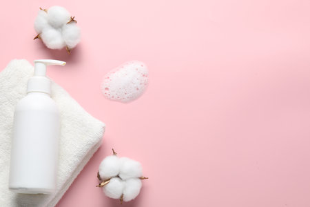 Flat lay composition with bottle of liquid soap and cotton flowers on pink background. Space for textの写真素材