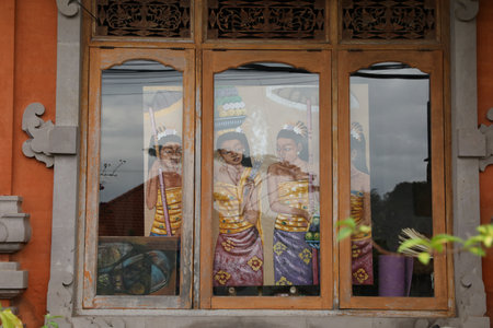 Bali, Indonesia - May 31, 2025: Drawing of women in traditional clothes, view through windowの写真素材