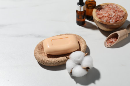 Soap bar, cosmetic products and cotton flower on white marble table, above viewの写真素材