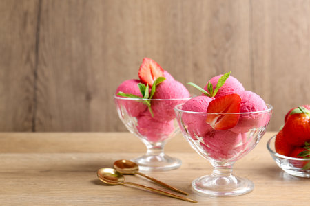 Refreshing sorbet, strawberries, mint and spoons on wooden table, closeup. Space for textの写真素材