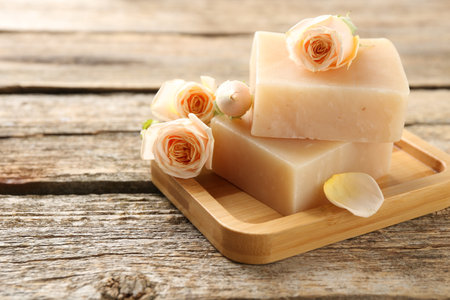 Soap bars and beautiful roses on wooden table, closeup. Space for textの写真素材