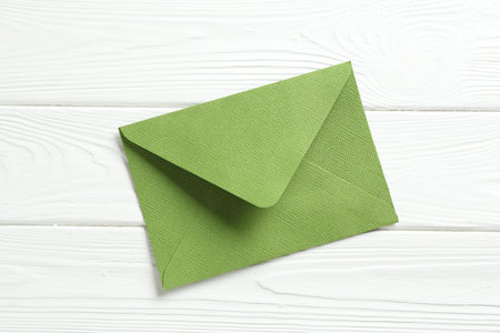 Beautiful invitation envelope on white wooden table, top view