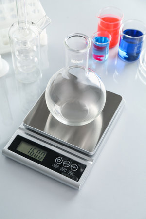 Scale with empty flask and other laboratory glassware on white mirror tableの写真素材