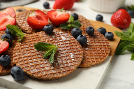 Tasty Dutch waffles (stroopwafels), mint and strawberries on white marble table, closeupの写真素材