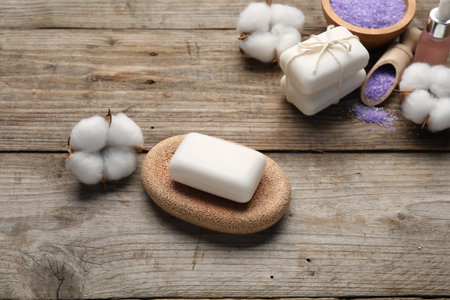 Soap bars, cosmetic products and cotton flowers on wooden table, above viewの写真素材