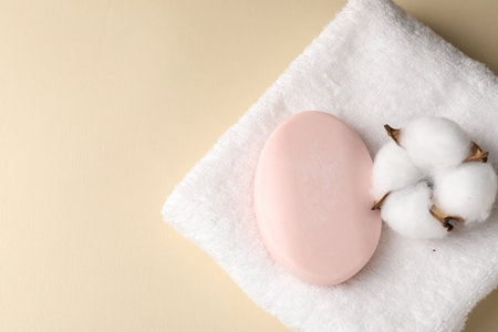 Soap bar, towel and cotton flower on beige background, top view. Space for textの写真素材