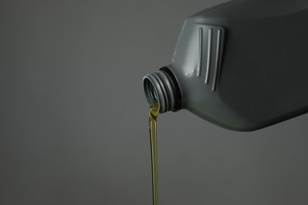 Pouring motor oil from canister on gray background, closeup. Space for textの写真素材
