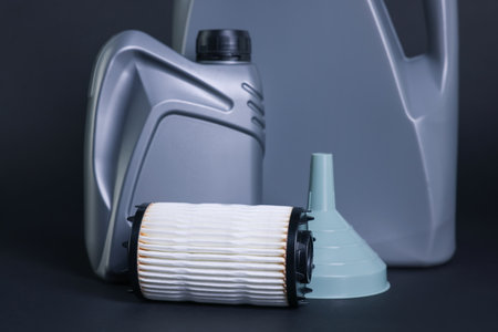 Motor oil in plastic canisters, filter and funnel on dark gray background, closeupの写真素材