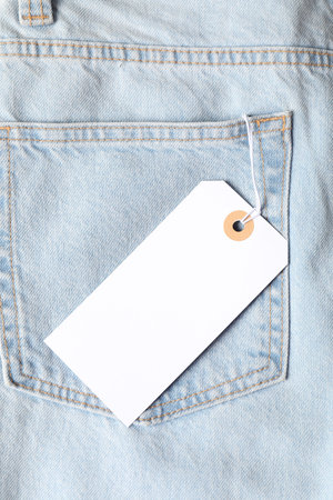 Cardboard tag on light blue jeans, top view