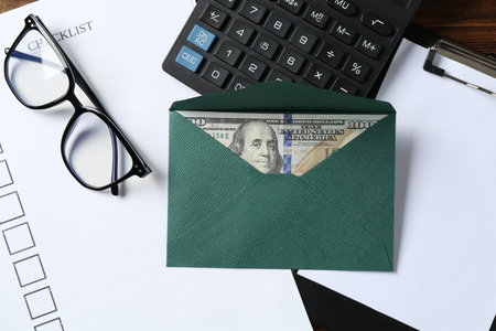 Money bonus. Envelope with dollar banknote, clipboard, checklist, glasses and calculator on table,...