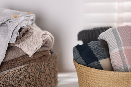 Wool sweaters and scarves in baskets on table indoors, closeupの写真素材