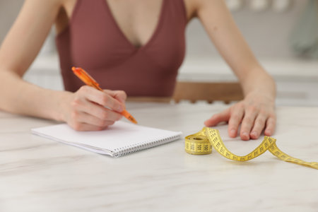 Woman developing diet plan at white marble table indoors, closeupの写真素材