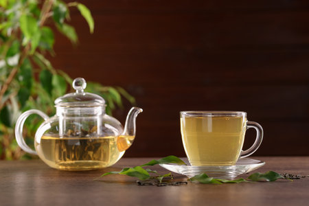 Cup of tasty green tea and teapot on wooden tableの写真素材
