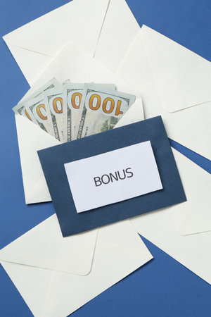 Envelopes with word Bonus and money on blue background, flat layの写真素材