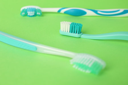 Different plastic toothbrushes on green background, closeupの写真素材