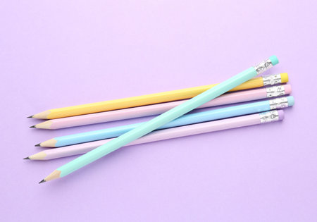 Many graphite pencils with erasers on violet background, flat lay