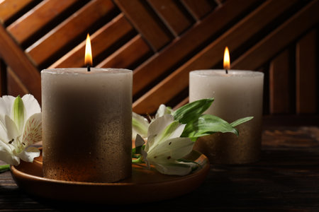 Burning candles and lily flowers on wooden table, closeupの写真素材
