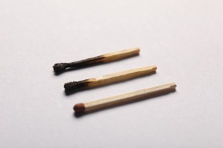 Burnt and whole matches on gray background, closeup