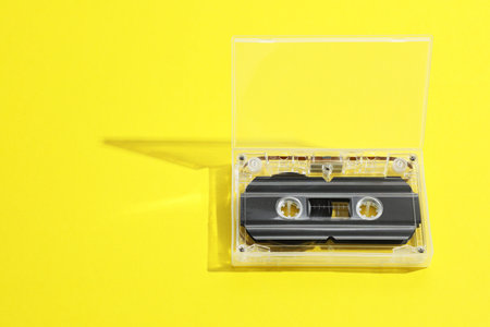 One audio cassette in open box on yellow background, above view. Space for textの写真素材