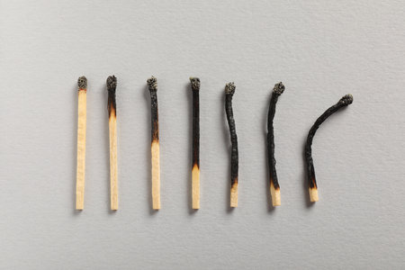 Burnt matches on gray background, flat layの写真素材