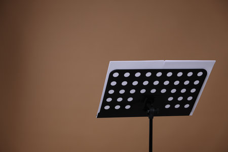 Stand with music sheets on dark beige background, space for textの写真素材